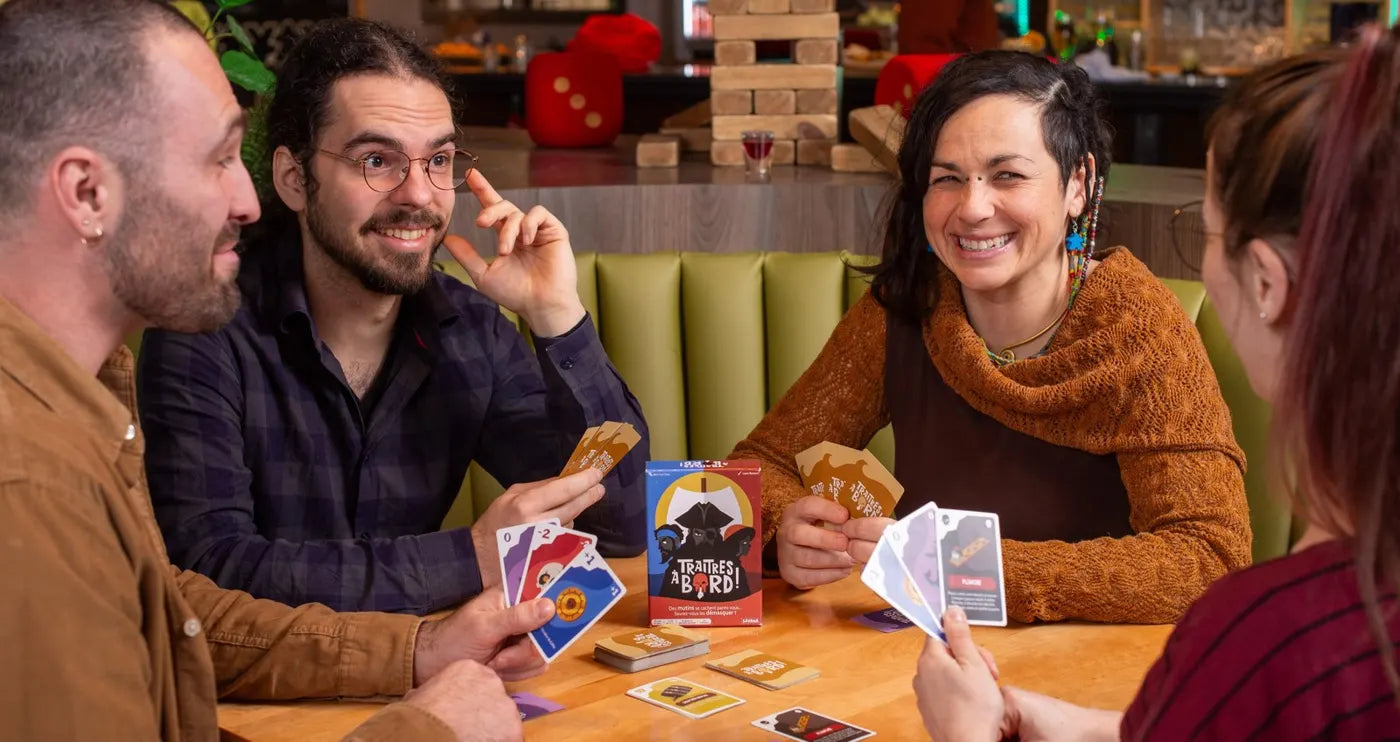 Quatre amis éclatent de rire pendant une partie de Traitres à Bord